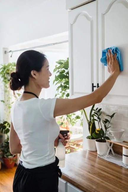 a-woman-in-a-green-shirt-and-black-gloves-vacuuming-a-gray-ottoman-5txz228u4eo